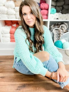 a woman is sitting on the floor in front of some yarn and crochet