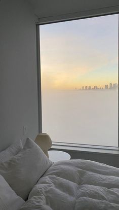 a bed sitting next to a window in a bedroom under a skylight with the city skyline seen through it