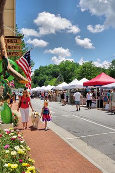 a woman and child walking down the street with an american flag on display behind them