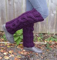 a woman's legs in purple knitted boots and leg warmers, standing next to a fence