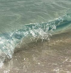 an ocean wave breaking on the beach with clear blue water and white foamy waves