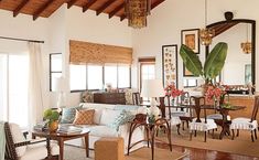 a living room filled with lots of furniture next to a window covered in plants and flowers