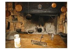 an old fashioned kitchen with pots and pans on the stove top in front of a fire place