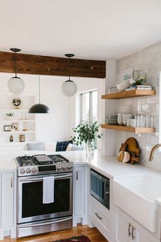 a kitchen with an oven, sink and open shelving on the wall above it