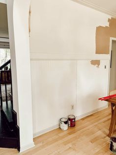 an empty room with some paint cans on the floor and a table in front of it