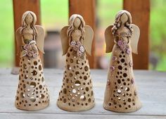 three ceramic angel figurines sitting on top of a wooden table