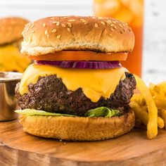 a cheeseburger with onion, lettuce and tomato on a wooden cutting board