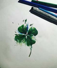 a drawing of a four leaf clover with watercolor pencils on the table next to it