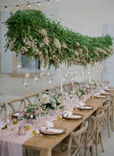 an instagram photo with flowers and greenery hanging from the ceiling over a long table