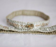 two white headbands with pearls on them sitting on top of a bed next to each other