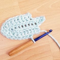 a crocheted object is laying on the floor next to a blue knitting needle