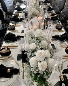 a long table is set with white flowers and candles for an elegant dinner or party