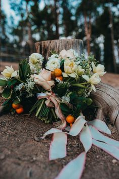 a bouquet of flowers sitting on top of a wooden stump in the dirt next to trees