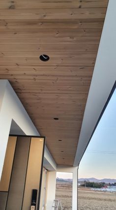 the ceiling is covered with wood planks and has an open door leading to another room