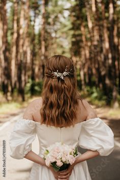 the back of a woman's head wearing a wedding dress and holding a bouquet