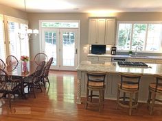 a kitchen and dining room with wood floors, white cabinets and an island in the middle