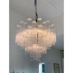 a large chandelier hanging from the ceiling in a room with white walls and windows