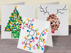 three cards decorated with christmas trees and pinecone decorations are on a wooden table