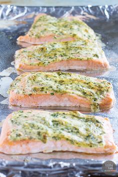 three salmon fillets with herbs and seasoning on them