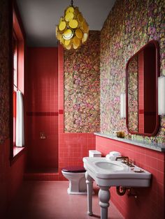 a bathroom with red walls and pink tiles on the floor, along with a white toilet and sink