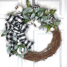 a wreath with white pumpkins and greenery is hanging on the front door,