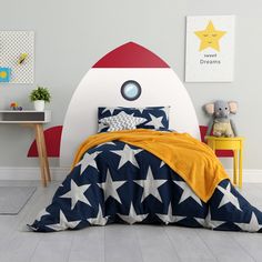 a child's bedroom with a rocket ship bed and yellow blanket on the floor