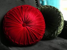 two red and green pillows sitting on the back of a couch next to each other