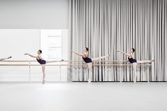 three ballerinas in black leotards and one is standing on a bar