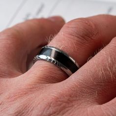 a man's hand with a wedding ring on his finger, next to a piece of paper