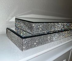 two crystal boxes sitting on top of a white dresser next to each other, covered in sequins