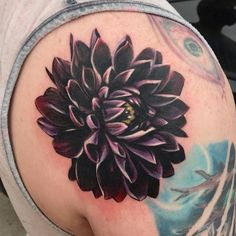 a close up of a person's arm with a flower tattoo on the back