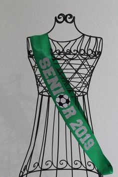 a green ribbon with the words soccer for everyone on it hanging from a wire rack