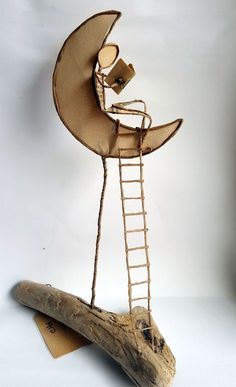 a sculpture made out of wood with a ladder going up to the moon on it