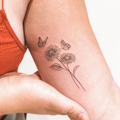 a woman's arm with three daisies and butterflies tattoo on the back of her left arm