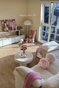 a living room filled with white furniture and pink flowers in vases on the coffee table