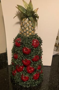 a pineapple with red apples and green leaves on it's top is shown