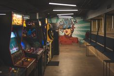 an arcade game room with several machines and video games on the walls, along with benches