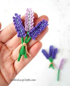 someone is holding some tiny crocheted lavenders in their hand and the flowers are purple