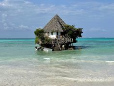 a boat is in the water next to a small house on stilts that are built into the ocean