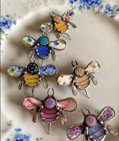 four bee brooches sitting on top of a white and blue flowered plate