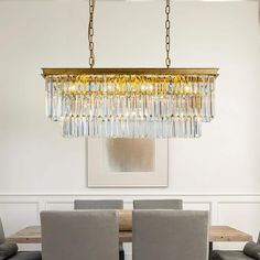 a chandelier hanging over a dining room table with grey chairs and gray walls