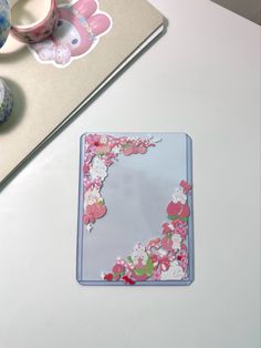 a white table topped with a pink and blue flowered coaster next to a cup