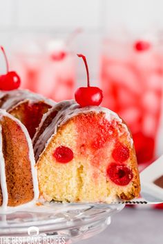 a bundt cake with white icing and cherries on top is sitting on a glass plate