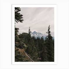 a mountain view with trees in the foreground and clouds in the sky above it