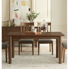 a dining room table with chairs and a painting on the wall in the back ground