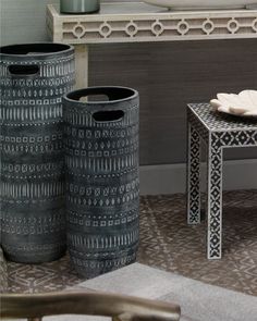 three black vases sitting next to each other on a table in front of a mirror