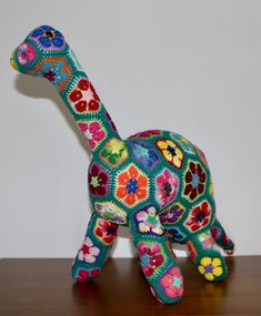 a colorful crocheted stuffed animal sitting on top of a wooden table