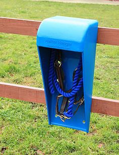 a blue box with two leashes hanging from it's side in front of a wooden fence