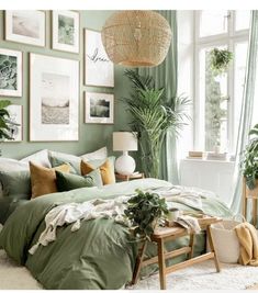 a bedroom with green walls and pictures on the wall above the bed, in front of a window