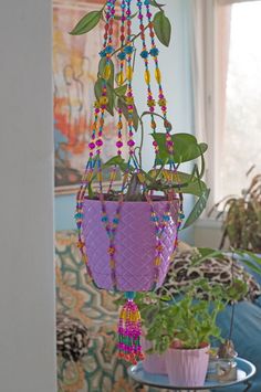 a hanging planter filled with plants and beads on a table in front of a couch